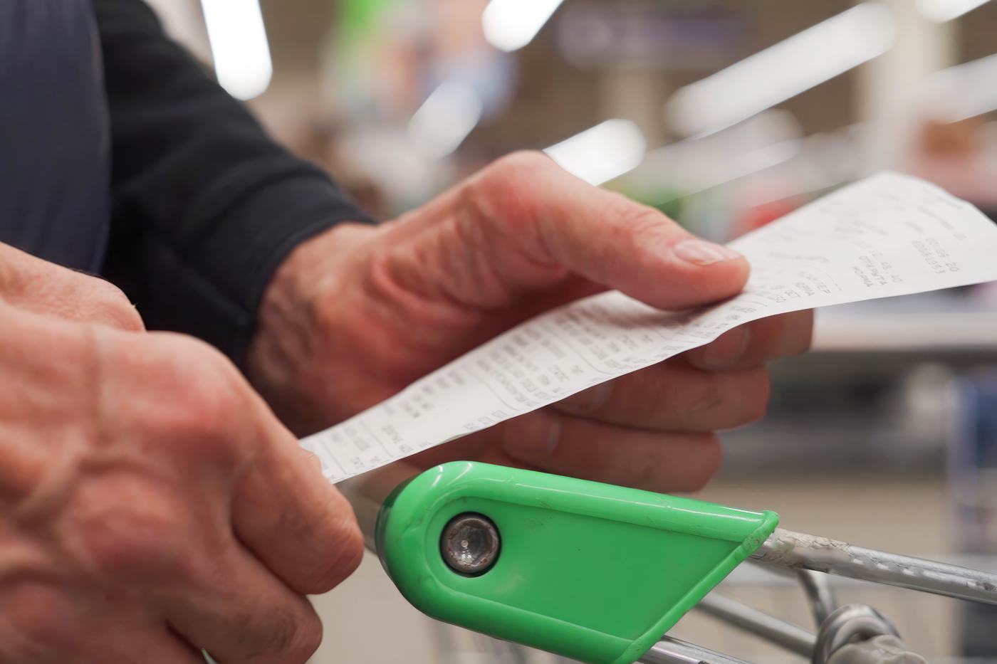 A shopper's hands holding a long grocery receipt